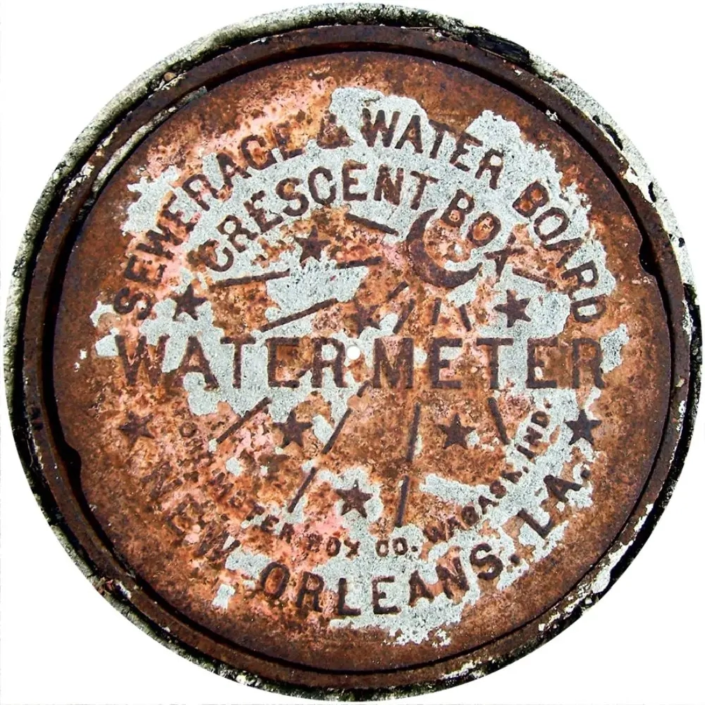 A rusty water meter cover with stars and the words " new rage & water board."