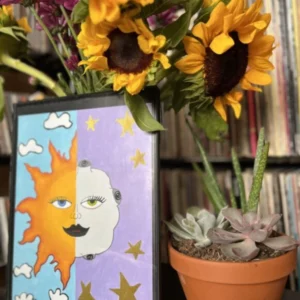 A vase with sunflowers and plants on top of a table.