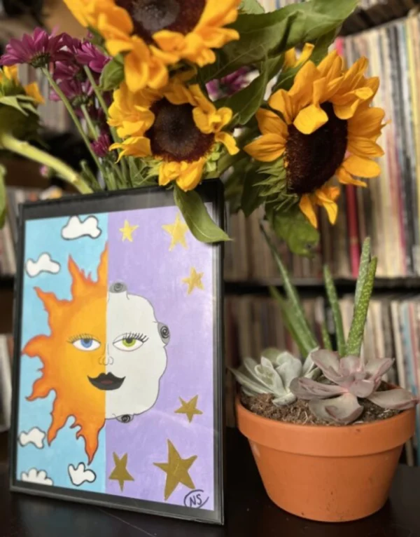 A vase with sunflowers and plants on top of a table.